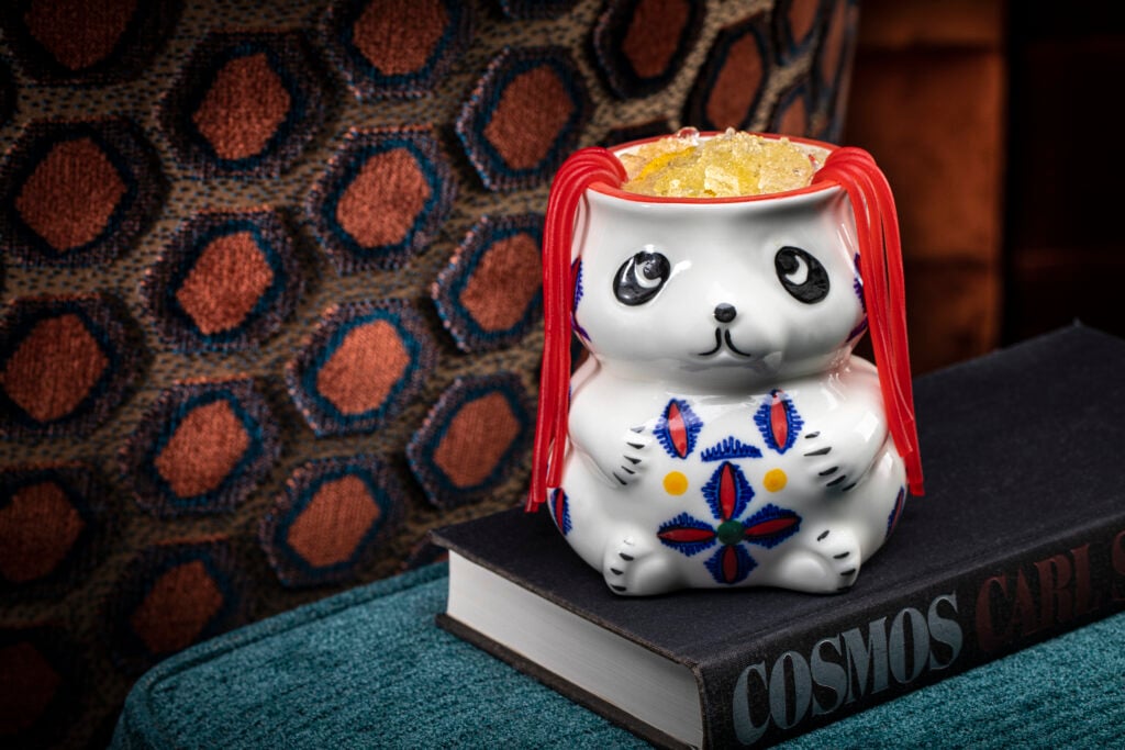a ceramic bear shaped cup with orange slices on top of a book