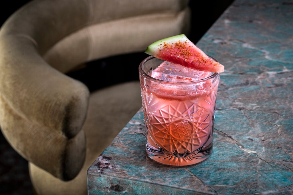 a glass with a drink and a slice of watermelon on top